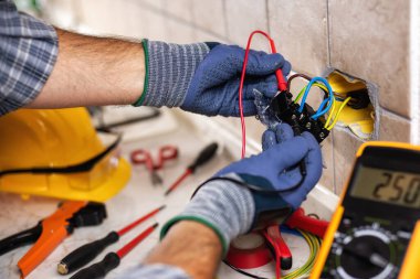 Elektrikçi, konut elektrik sisteminin prizlerindeki voltajı ölçüyor. İnşaat endüstrisi. 