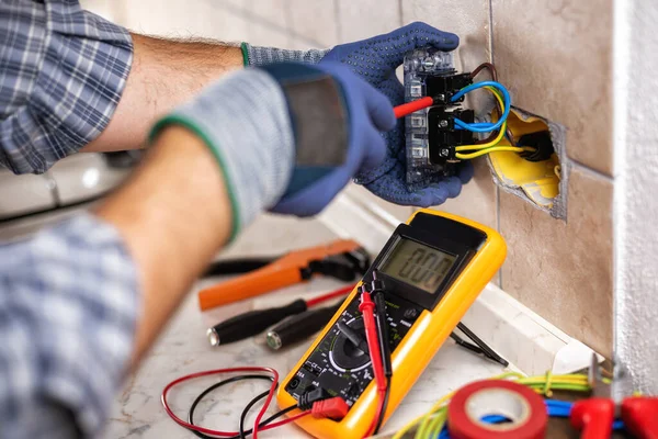 Electrician at work with screwdriver fixes the cable in the sockets of a residential electrical system. Construction industry.