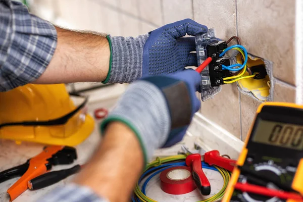 İşteki elektrikçi tornavidayla birlikte konut elektrik sisteminin prizlerini tamir ediyor. İnşaat endüstrisi. 