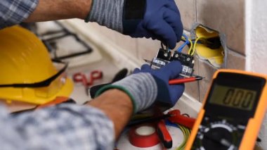 İşteki elektrikçi tornavidayla birlikte konut elektrik sisteminin prizlerini tamir ediyor. İnşaat endüstrisi. Görüntü.