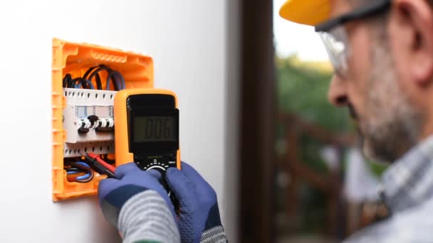 試験機の作業中の電気技師は 住宅設置の電気パネルの電圧を測定します 建設業 — ストック動画