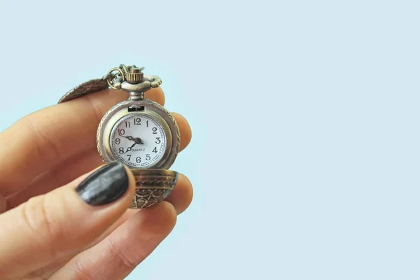 A watch in female hand isolated on light blue background