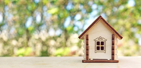 Close view of wooden toy house on wooden surface with blurry background