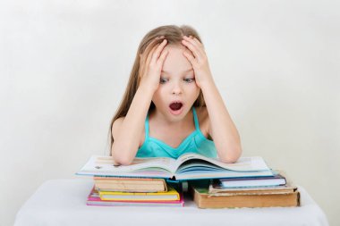 Küçük kız ders çalışıyor ve arka planda kitap okuyor. Eğitim ve okul kavramı -