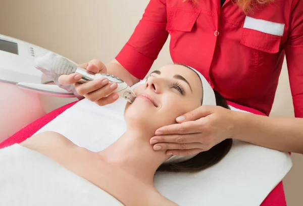 Rejuvenating facial treatment. Model getting lifting therapy massage in a beauty SPA salon. Exfoliation, Rejuvenation And Hydratation. Model and Doctor. Cosmetology.  Close up, selective focus.