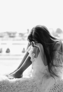 Üzgün küçük kız pencerenin önünde tek başına oturuyor. Ağlayan çocuk yalnızlığı. Çocuklar ve duygular. Alerji, hastalık, depresyon, stres konsepti.