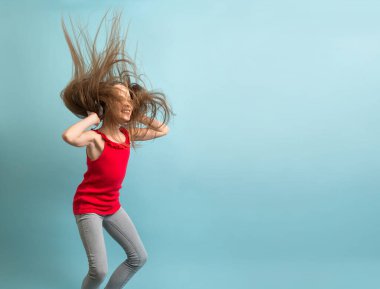 Gri kulaklıklı, uzun saçlı neşeli kız müzik dinler, dans eder, zıplar ve eğlenir..