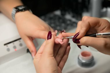 Çivi uzatma prosedürleri, jöle üzerine çivi çakma ustası. Kadın manikür yaptırıyor. Yaklaş, seçici odaklanma.