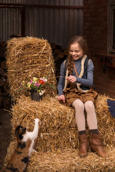 幸せな小さな子供の女の子は農場で猫と遊んでいます ペットが干し草の上に座っている子供の肖像画 — ストック写真