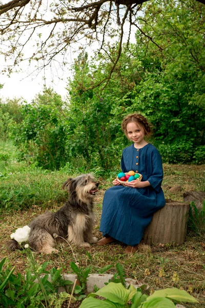 庭で大きなペット犬と遊んでイースターカラーの卵を持つ小さな笑顔の子供の女の子 イースターの装飾と子供 屋外季節の肖像画 — ストック写真