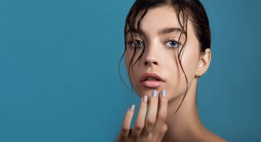 Temiz cildine ve su damlasına sahip genç ve güzel bir kadın yüzüne dokunuyor. Güzellik modelinin doğal çıplak makyajlı portresi cildini losyonla nemlendiriyor. Spa, cilt bakımı ve sağlık. Kapat, arkaplan, kopyala.