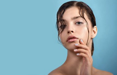 Temiz cildine ve su damlasına sahip genç ve güzel bir kadın yüzüne dokunuyor. Güzellik modelinin doğal çıplak makyajlı portresi cildini losyonla nemlendiriyor. Spa, cilt bakımı ve sağlık. Kapat, arkaplan, kopyala.