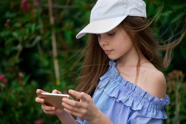 かわいい女の子のテキストメッセージや外のスマートフォンでゲームをプレイ 子供は近代的な技術を使う 子供は自画自賛 音楽鑑賞 ダンス — ストック写真