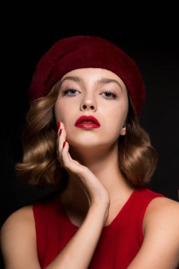 Güzel genç bir kadının portresi kırmızı elbiseler ve bereyle mükemmel genç bir ten, kırmızı dudaklar ve tırnaklar. Koyu arkaplanda parlak kırmızı makyajlı ve manikürlü bir model.