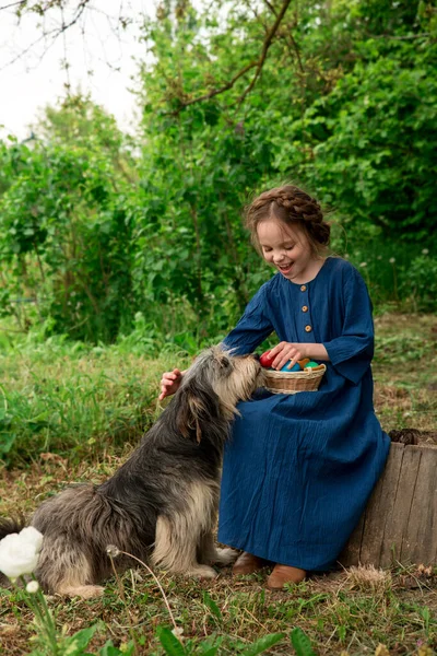 庭で大きなペット犬と遊んでイースターカラーの卵を持つ小さな笑顔の子供の女の子 イースターの装飾と子供 屋外季節の肖像画 — ストック写真