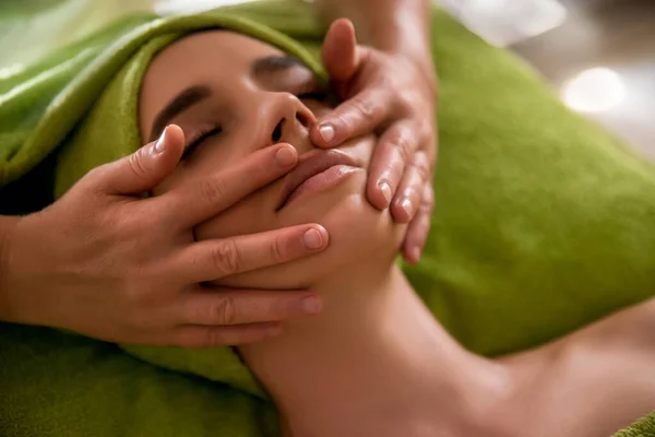 Face massage. Spa skin and body care. Close-up of young woman getting spa massage treatment at beauty spa salon. Facial beauty treatment. Selective focus