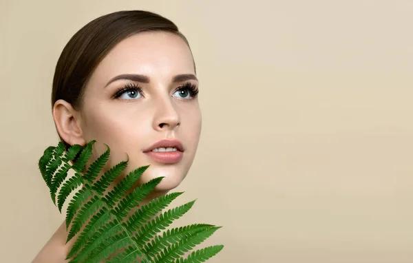 自然なメイクで若い美しい笑顔モデル 長いまつ毛とシダの緑の葉 スキンケア ウェルネス 美とスキンケアのコンセプト — ストック写真