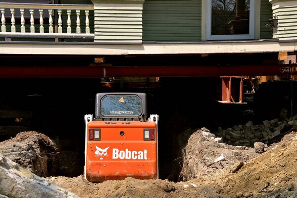 FARGO, NORTH DAKOTA, May 14, 2018:  The Bobcat skid steer moving earth from under an old house is headquartered in West Fargo, North Dakota.