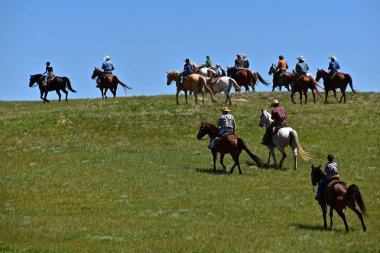 Kimliği belirsiz kovboy ve otları bir toparlama ve oturum markalaşma sonra çiftliğe geri başlı prairies üzerinde ata binmek.