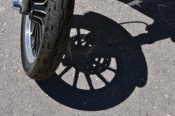 摩托车的前轮把它的影子投射在水泥垫上 — 图库照片