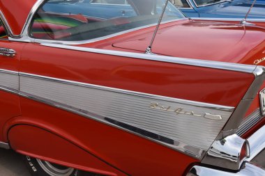 WEST FARGO, NORTH DAKOTA, June 27, 2018: The West Fargo Cruise night occurs each 3rd Thursday night in the summer months and features classic cars as this side profile of the fins of a red four door 1957 Chevy. clipart