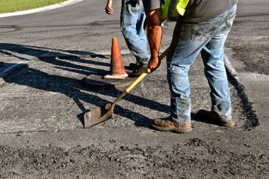 İnşaat işçileri kir darbe ve asfalt bir fırtına kanalizasyon kapağı çevresinde yeni bir katman için izin veren bir beton yama uzak atık.