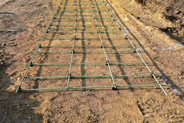 Bir gelecekteki kaldırım yapım aşamasında yerde inşaat demiri ile kum tabakası üzerinde uzunluğudur