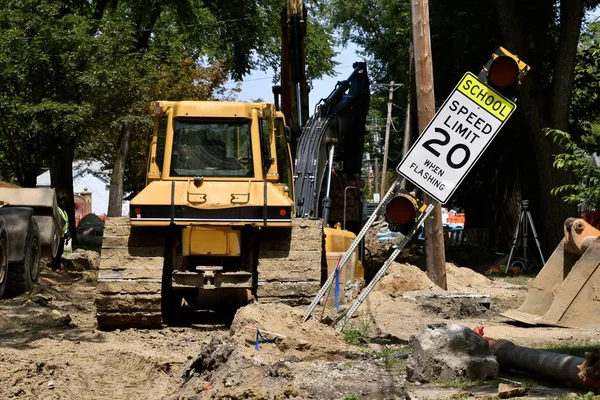 A construction road and street repair scene leave a mess of dirt, equipment and street signs
