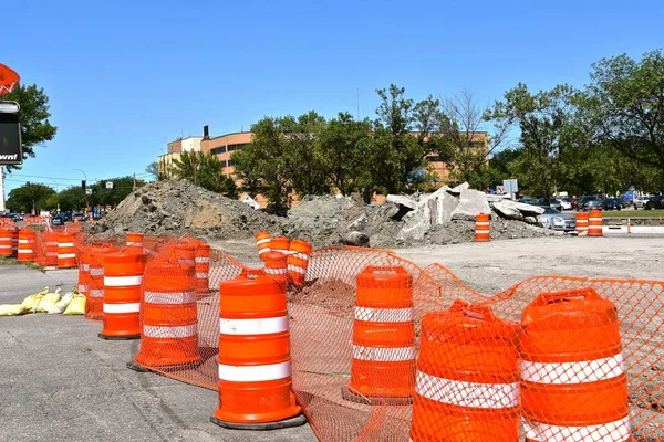 Orange barrels block traffic from a major road repair and construction site within a city.