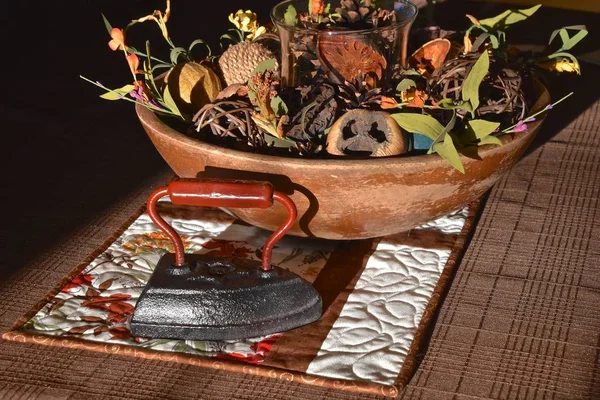 An old metal flat iron shares decorating space with a wooden bowl of guards and fall items.