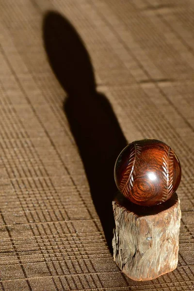 一个完美的圆球核桃与雕刻针休息在一个木制的立场上 并抛出它的影子在桌布 — 图库照片