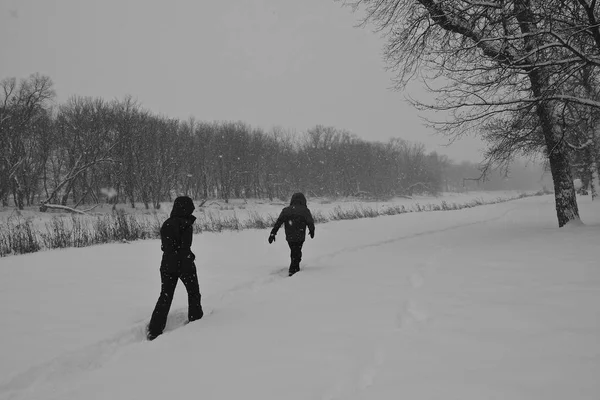 つの正体不明のハイカーは 吹雪の中で深い雪の中を歩いています — ストック写真