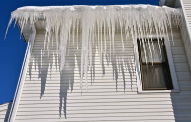 Büyük buz sarkıtları asmak ve neredeyse iki kat uzunluğunda kapsayan kendi gölgeler bir iki hikaye evden atmak,