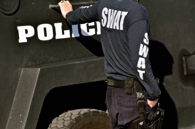 Swat'ın dışında bir polis aracının yanında duran bir üye.