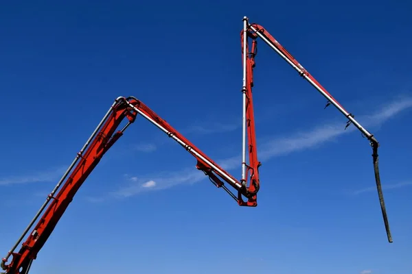 A super pumper ready mix truck supplies wet mud(concrete) to a the foundation of a construction building site through a hose connected to jointed hydraulic arms