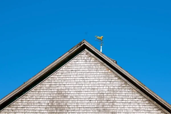 The back end of a barn displays a weather vane of a horse trotting.
