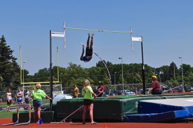 Kimliği belirsiz bir sırıkla atlamacı çıtayı temizlemek için havada asılı kaldı..
