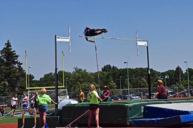 Kimliği belirsiz bir sırıkla atlamacı çıtayı temizlemek için havada asılı kaldı..