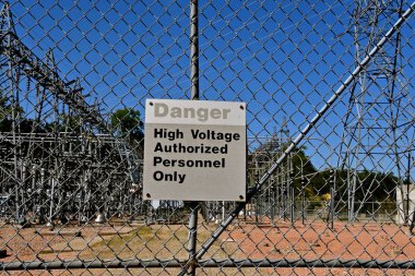 Elektrik santralinin önünde yüksek voltaj tabelası var.