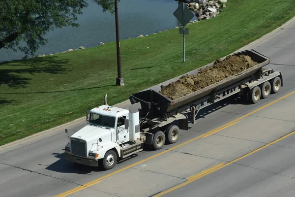建設現場から大量の埋め立て地を運ぶ荷積みトラックが高速道路を下っていく — ストック写真