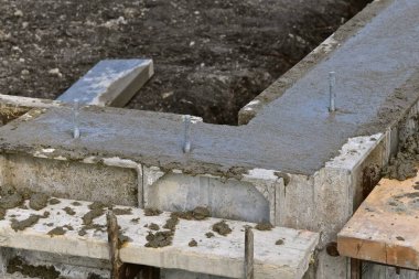 Taze çamurun (demir cıvatalar eşik plakalarını beklerken beton döküldüğü bir formun köşesi.