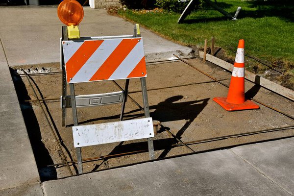 Ремонтируется участок подъездной дорожки на жилом доме с отображением предупреждающих конусов
.