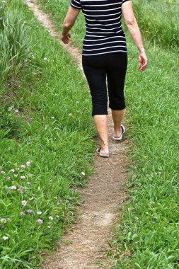 Bir kadın yürüyor ve sandaletleriyle dolambaçlı bir yolda egzersiz yapıyor..