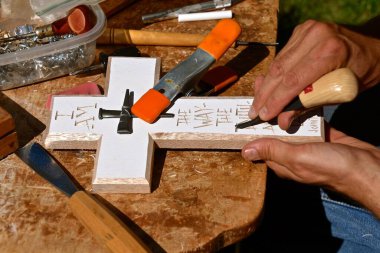 Bir keski oymacısı haç şeklinde bir tahta üzerinde İncil 'in sözleriyle çalışır.. 