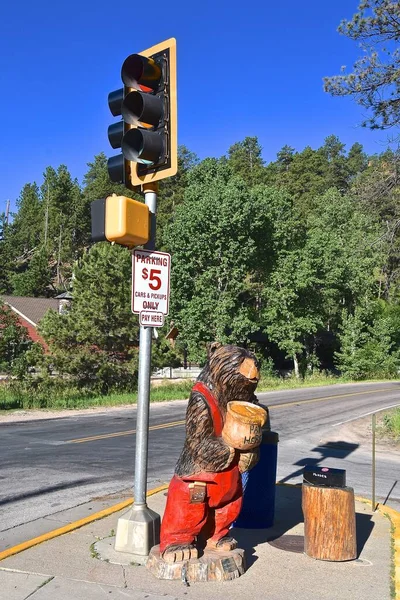 A chainsaw carved bear serves as a collecting point for a parking fee.