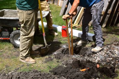 Bölünmüş saplı bir post-hole kazıcı bir direği desteklemek için gerekli toprağı taşıyor