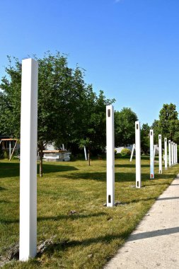 A line of white vinyl posts are in place for a new backyard fence. clipart