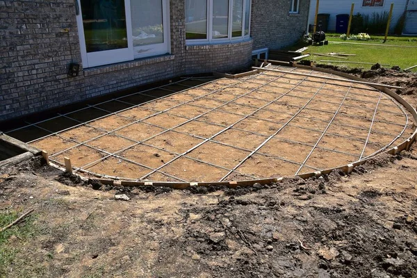 A backyard concrete patio is being created in the shape of a semi-circle