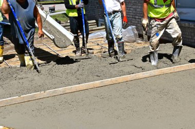 Beton işçileri avluyu ıslak çamurla dolduruyor, tarıyor ve düzleştiriyor..
