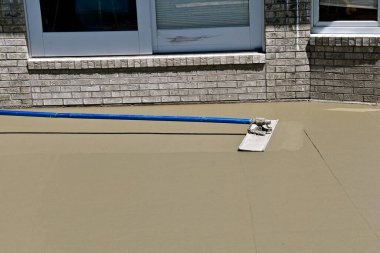 Yeni ıslak beton projesinde bir boğayla betonu düzleştirip düzleştirmek.